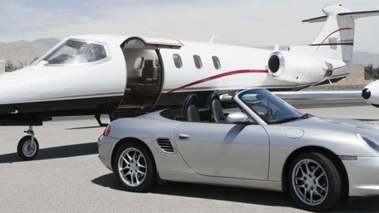 Luxury car parked next to a private jet.