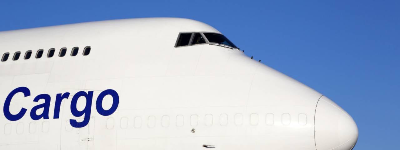 Front nose of large white cargo plane with the word cargo written on it in blue.