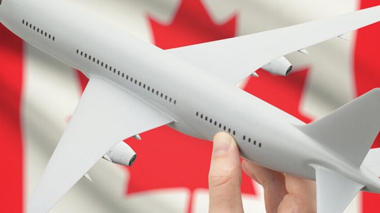 Hand holding plane in front of Canadian flag