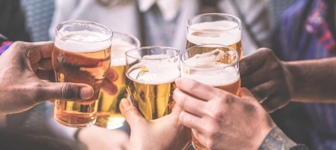 A close up of a group of friends raising a toast with their beers