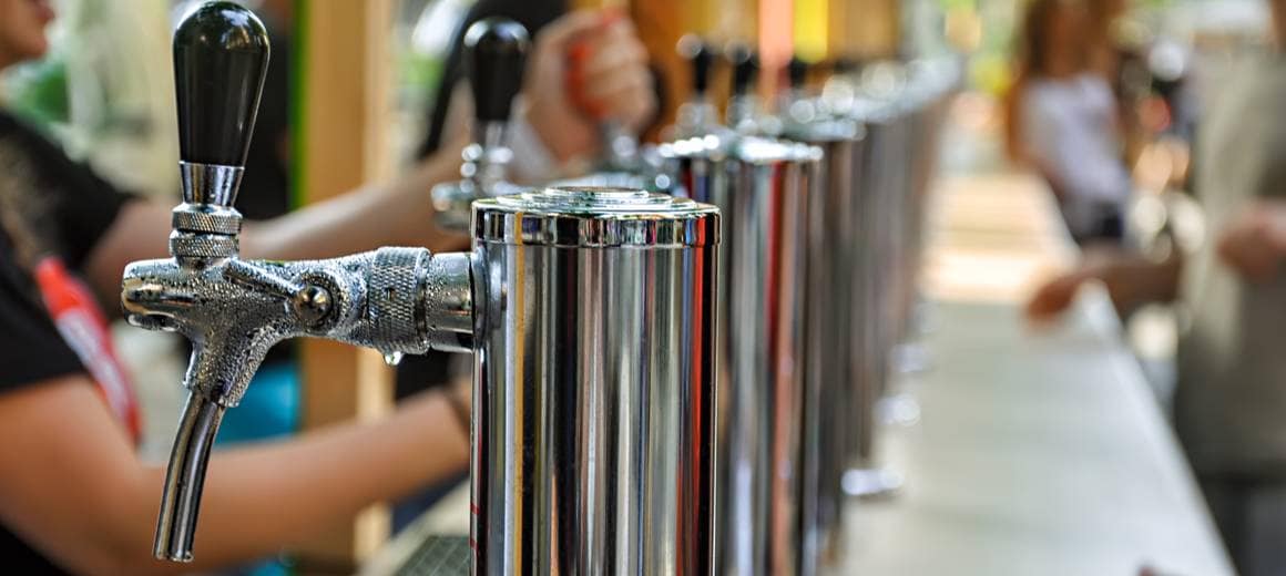 Row of silver beer taps at a counter