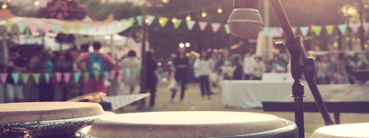 Photo taken from the stage of a music festival with drums and a microphone in the foreground.