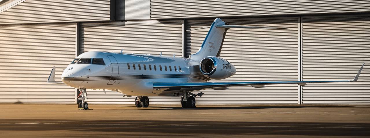 While blue and yellow Bombardier Global 5000 luxury jet on the runway.