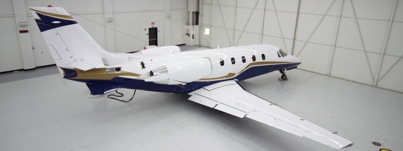 Brand new white, blue and gold private jet in a hangar.