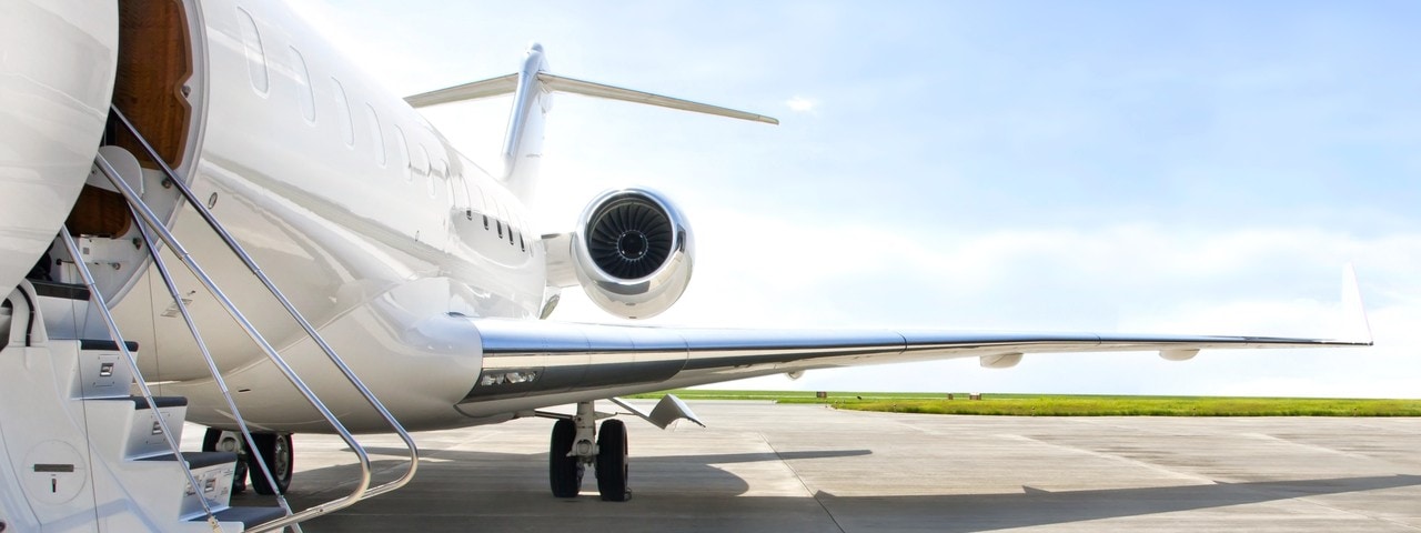 Gleaming white private jet on runway with lowered airstairs.