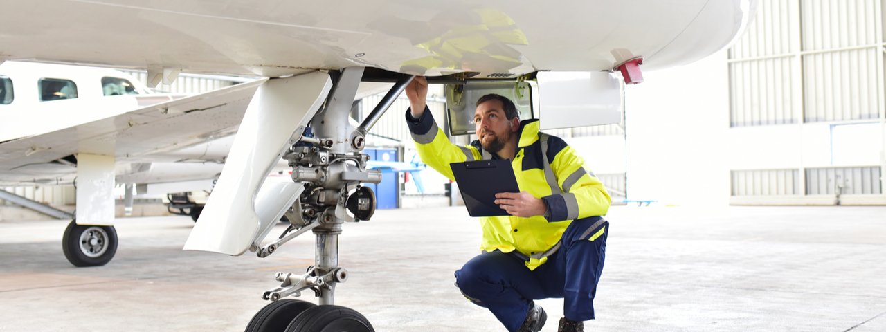 Official ground personnel leading a pre-buy inspection and checking the hydraulic system of the landing gear of an aircraft