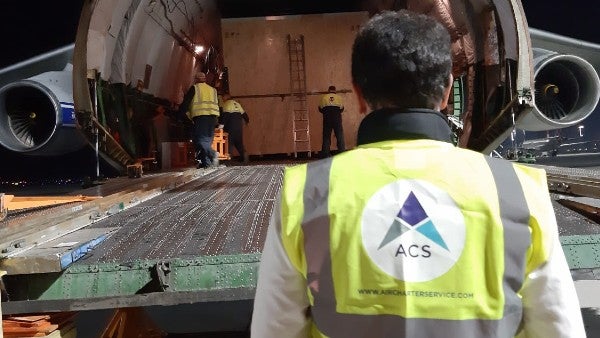 An ACS employee loading cargo into a cargo plane.