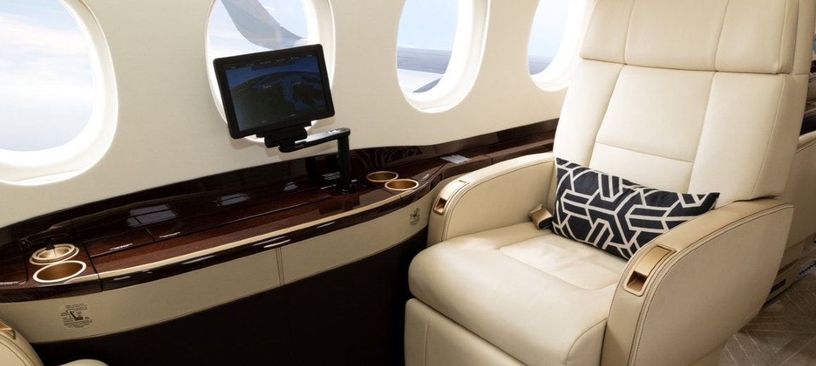 White leather seat interior of business jet with small TV screen