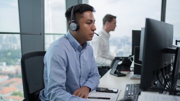 A man wearing a headset in the office with a digital map and flight path in front of him.