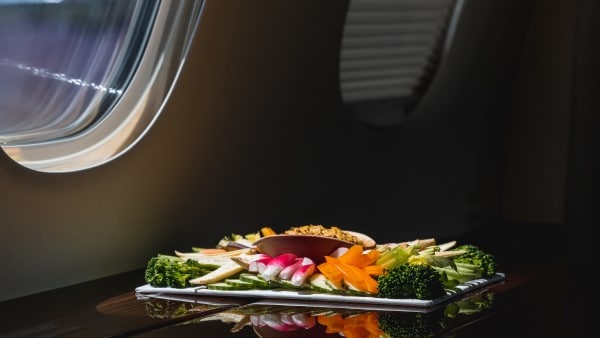 A platter with fresh vegetables and other finger food on a table on a private jet.