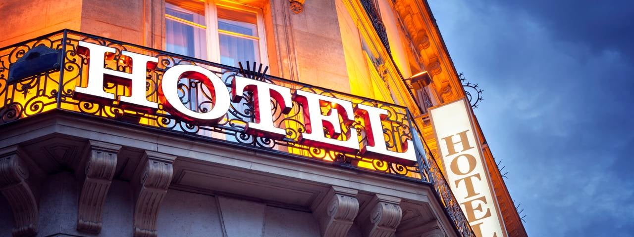 An illuminated hotel sign at night in Paris.