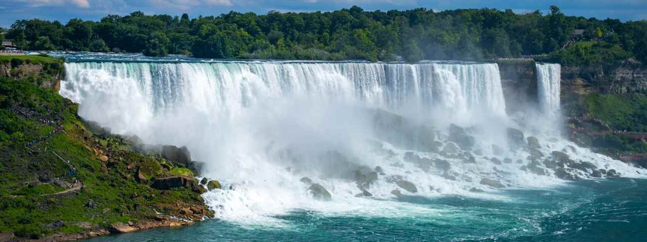 A side view of some of the Niagara Falls with rising mist from the rocks below