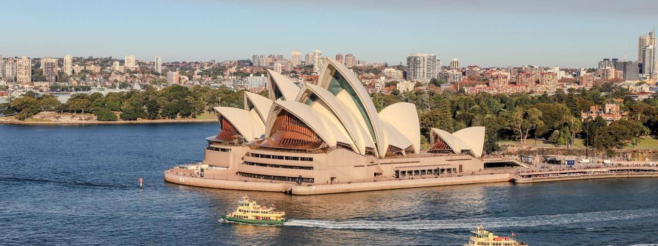 A view of the Sydney Opera House as two ferry boats go by.