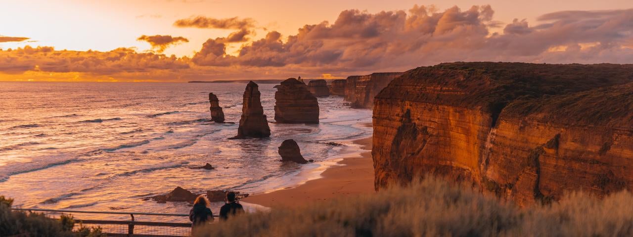 Two people visiting the 12 Apostles in Australia.
