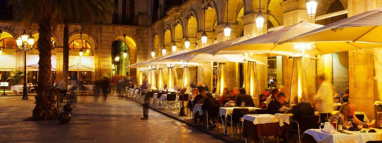 A photograph of street restaurants at Placa Reial in Barcelona on a winter evening.