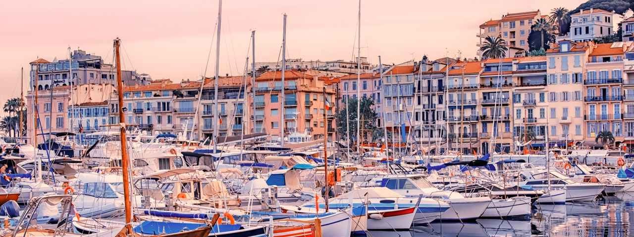 Cannes in the early morning sunrise light viewed from the old harbor with sailing boats in the foreground.
