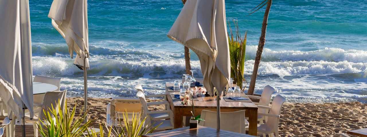 Beach restaurant in Cairns with the ocean just in front of the tables and umbrellas.