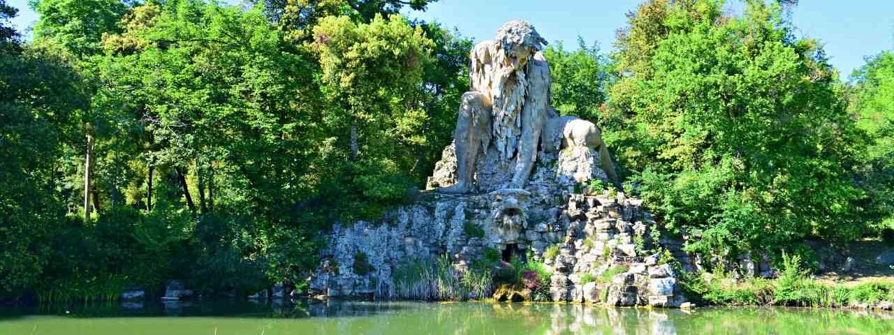 A scenic statue of a man overlooking a pond surrounded by greenery