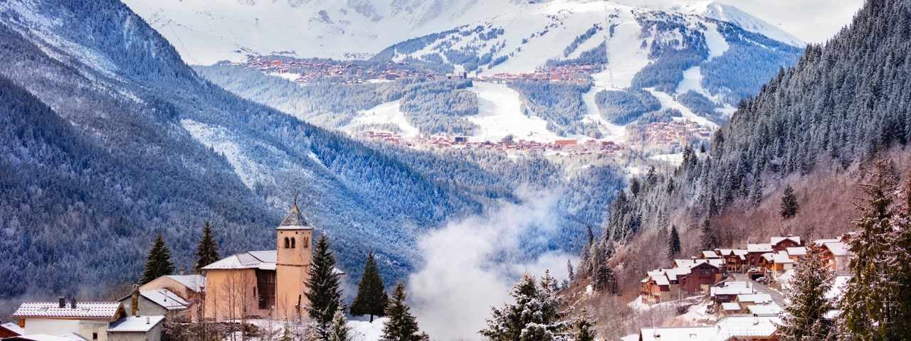 Aerial view of a quaint village and snow-covered mountains in Courchevel.