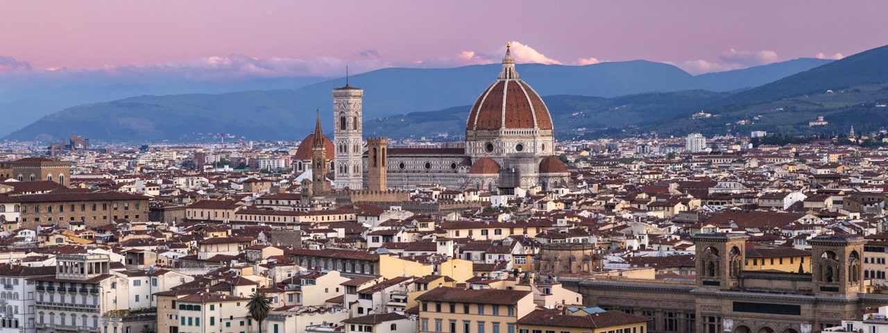 An aerial view of Florence at sunset with the Duomo sticking out from surrounding buildings 