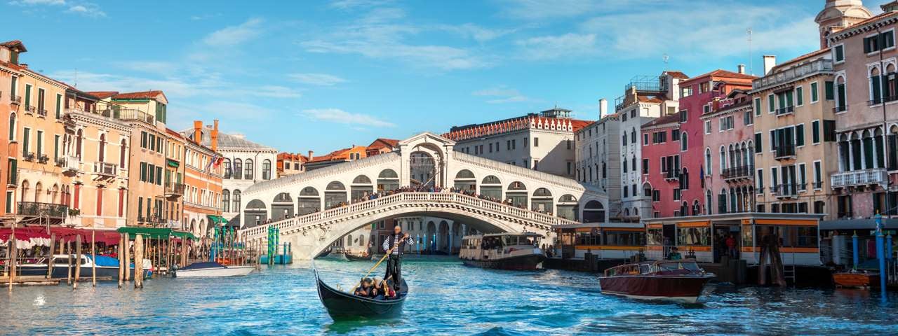 A canal and boat in Venice surrounded by traditional houses.