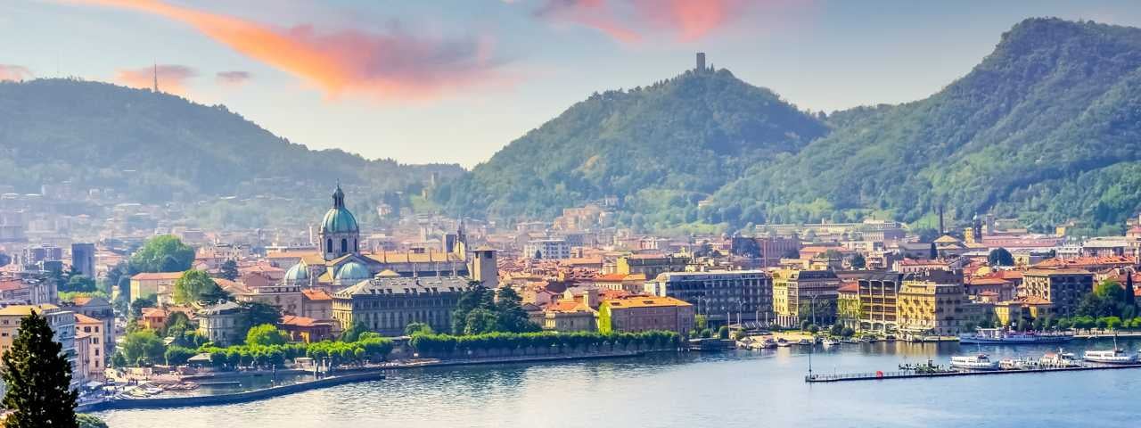 A town on the shores of Lake Como with mountains in the background.