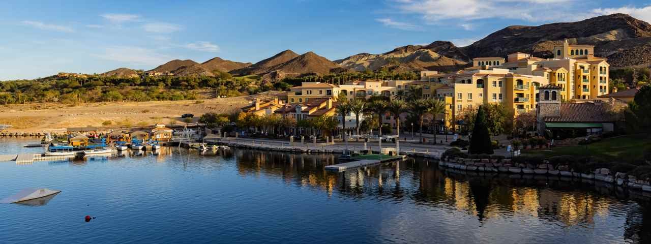 A view of Las Vegas Lake with boats and houses on the edge and mountains in the background