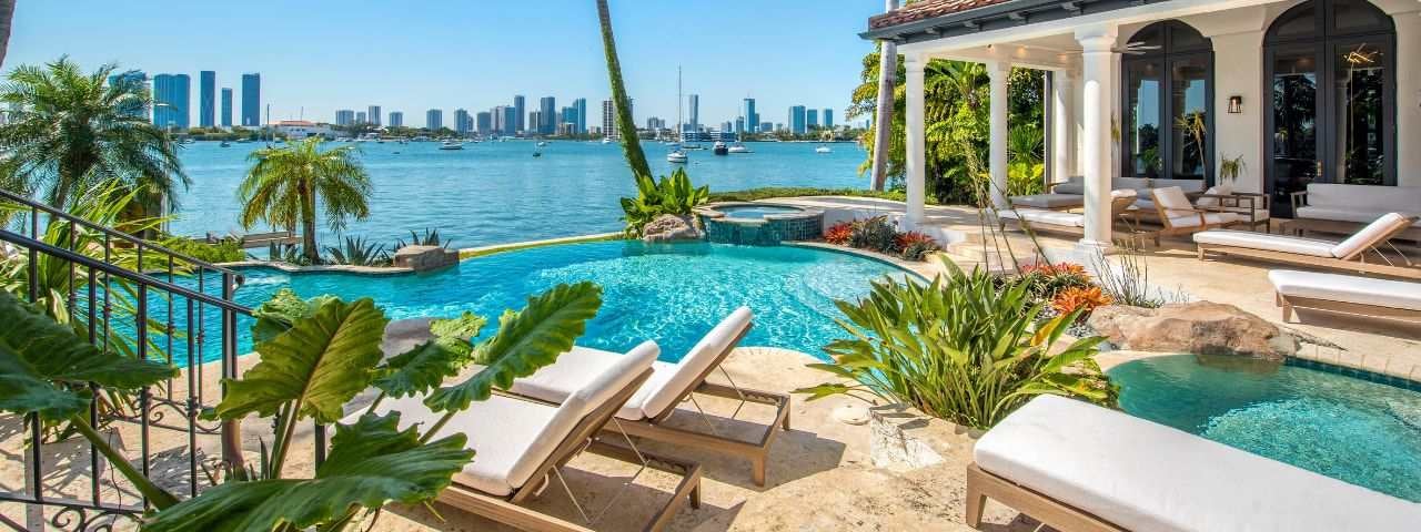 A luxurious resort with a clear swimming pool in Miami, with the ocean directly next to it.
