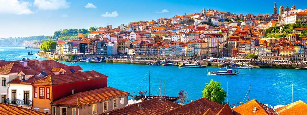 A view of the Porto harbour with colourful houses on either side of it.