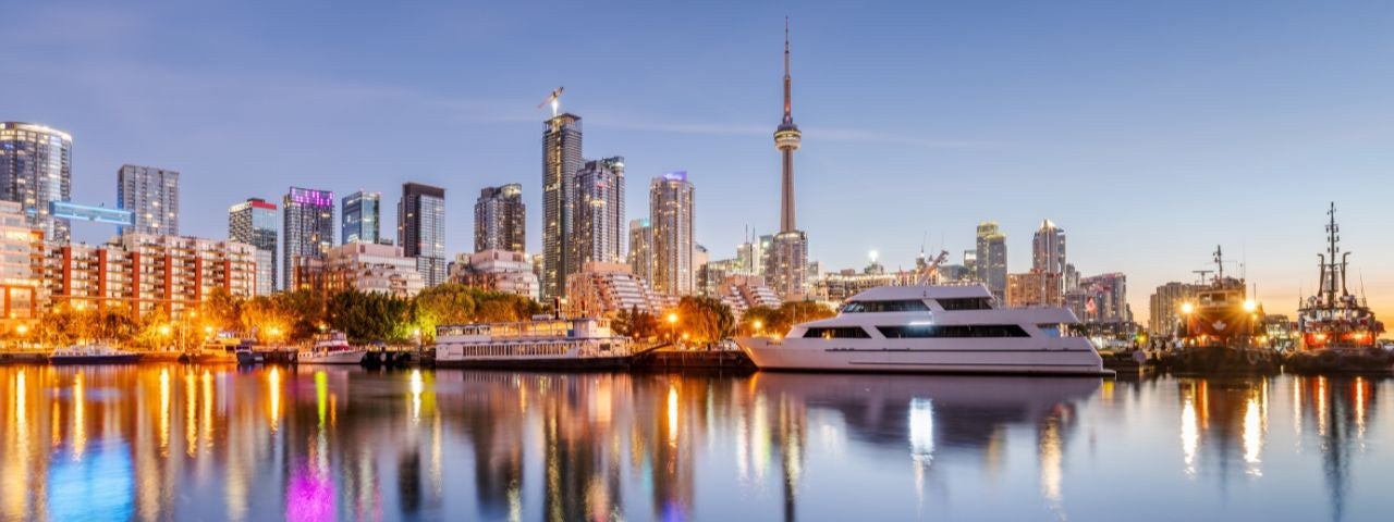 Toronto’s beautiful skyline reflected in the calm harbor waters at dawn.