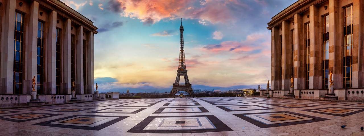 A view of the Eiffel Tower during sunset with a building in the foreground