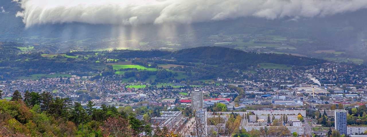 A panoramic view of Chambéry with sun rays bursting through the cloud cover.