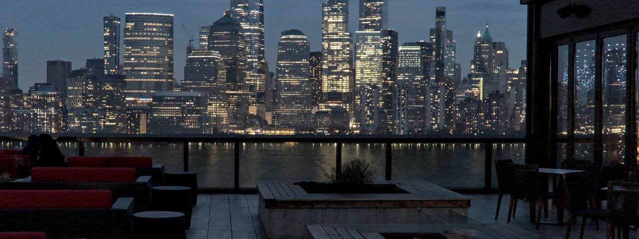 A rooftop bar restaurant with views of the Downtown Manhattan skyline.