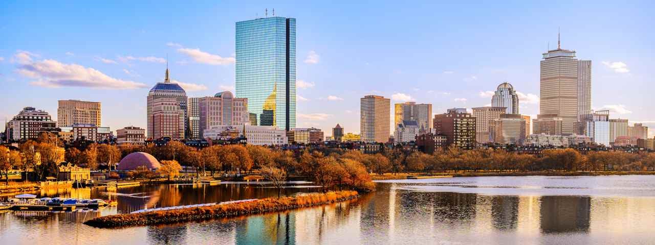 The city of Boston on a sunny autumn day, bathed in light, with water in the foreground