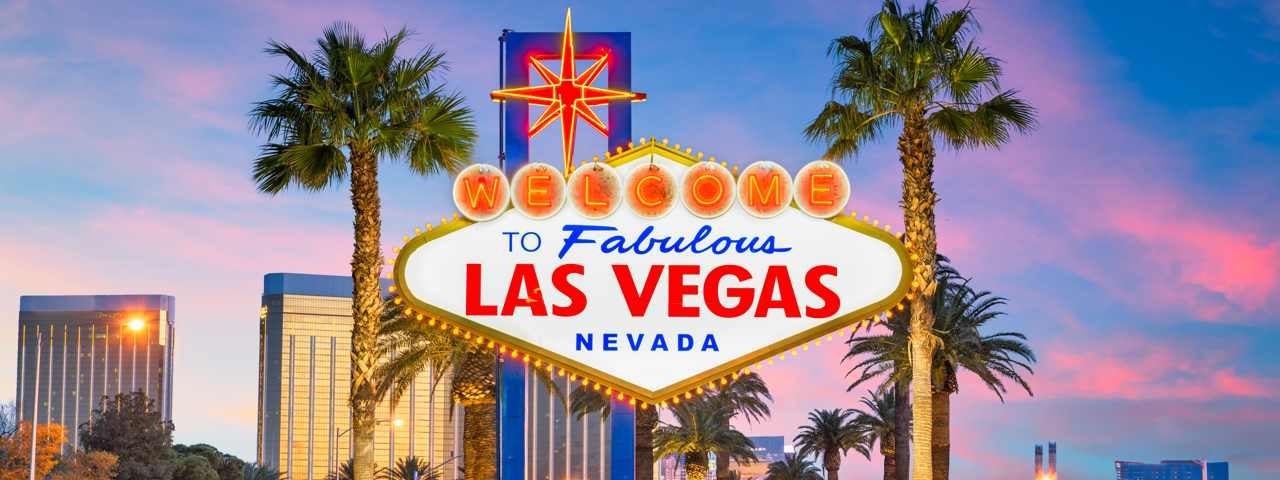 The famous Las Vegas sign flanked by two palm trees and the sunset in the background