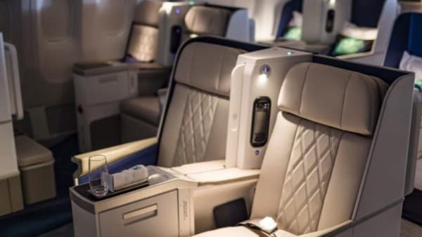 Premium seating on board a passenger aircraft with an extendable divider between seats for greater privacy.