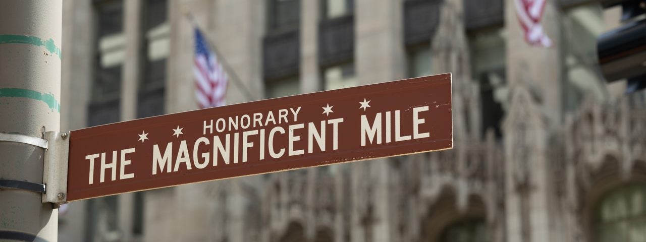 A sign for Chicago’s Magnificent Mile with buildings in the background. A sign for Chicago’s Magnificent Mile with buildings in the background.