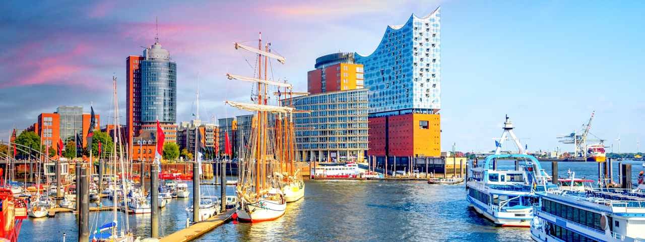 A harbour in Hamburg with boats parked in the foreground and the city in the background.