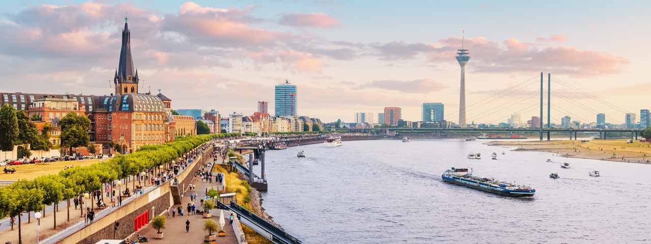 Soft evening light on the riverfront of Düsseldorf’s Old Town with a boat on the river.