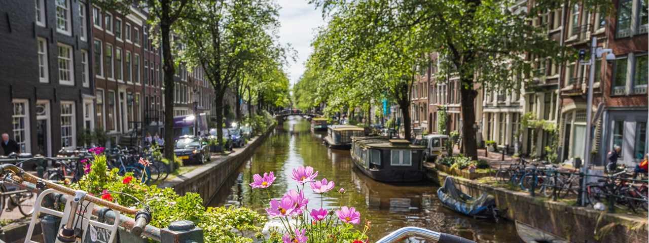 A canal and narrowboats with quaint houses on a spring day in Amsterdam.