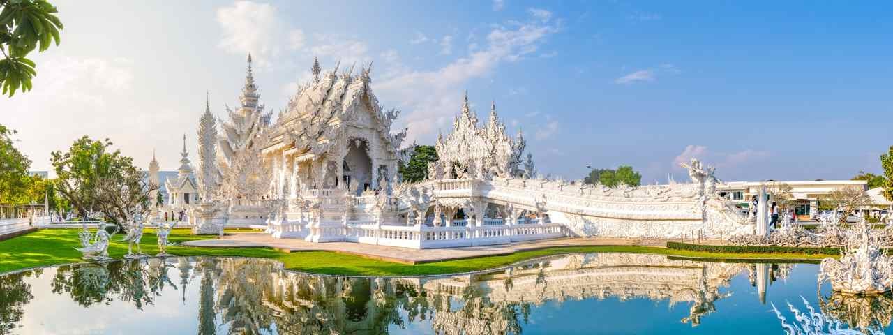 The White Temple in Chiang Rai on a sunny day with water in the foreground