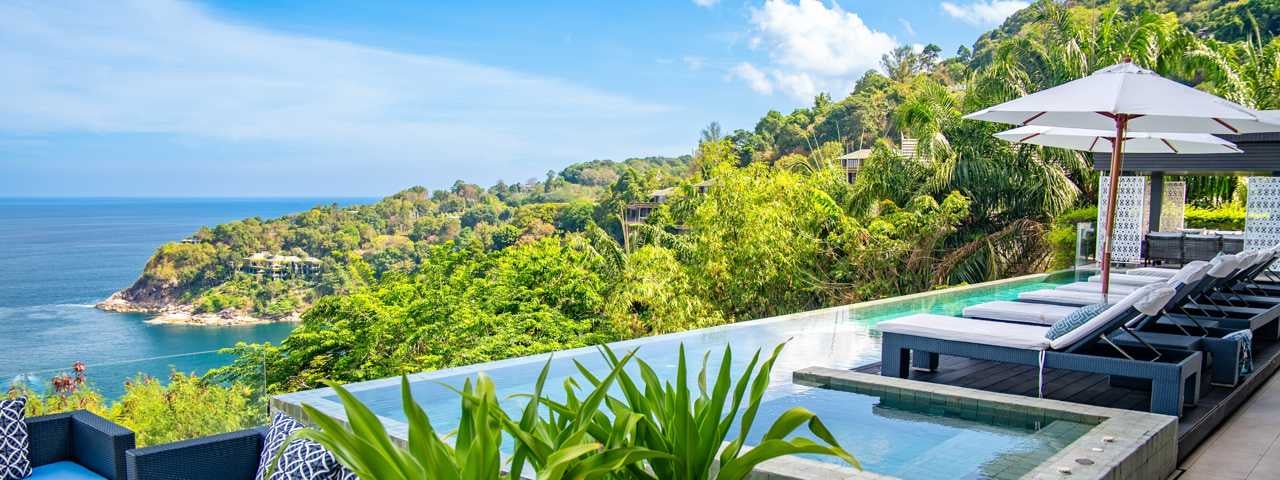 A swimming pool and loungers in Phuket overlooking the beach and ocean