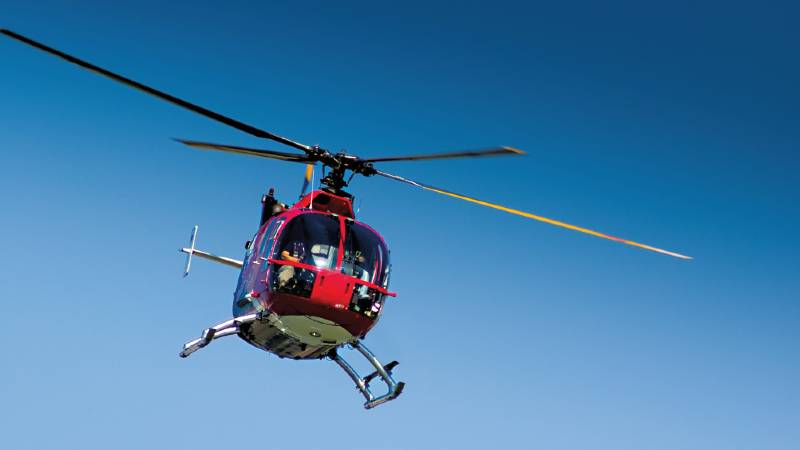 A red helicopter flying through the air.