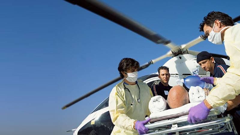 Medical staff moving an injured man on a gurney from a helicopter. 