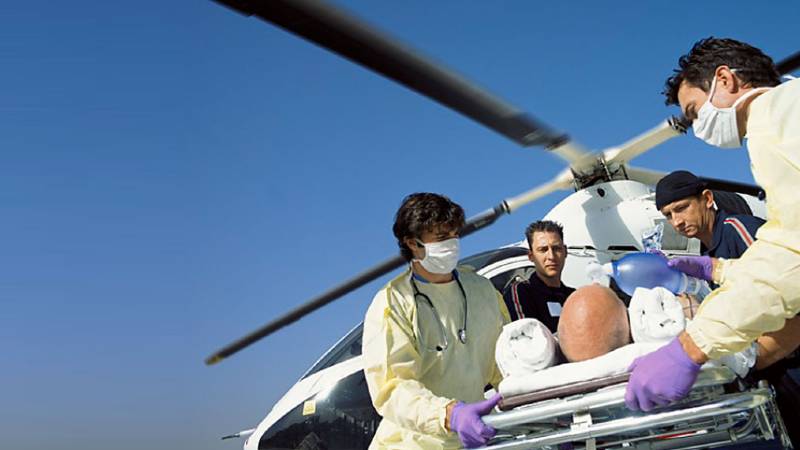 Medical crew move a man on a stretcher from a helicopter.