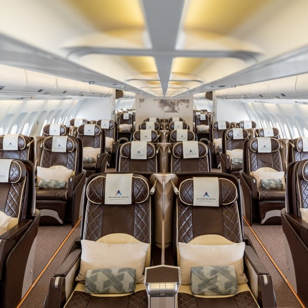 The interior of an aircraft with many seats with ACS branding.