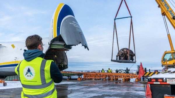 A crane is prepping pallets of cargo for loading onto a plane.