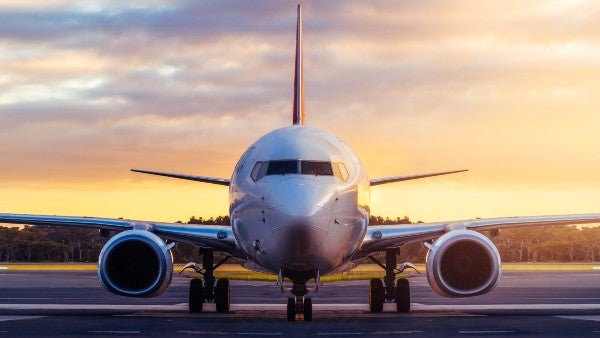 Front view of an airplane flying in front of large clouds.