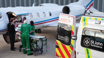 Medical staff and aircraft crew helping to offload a patient from a private jet.