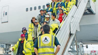 People exiting a large aircraft via a staircase.